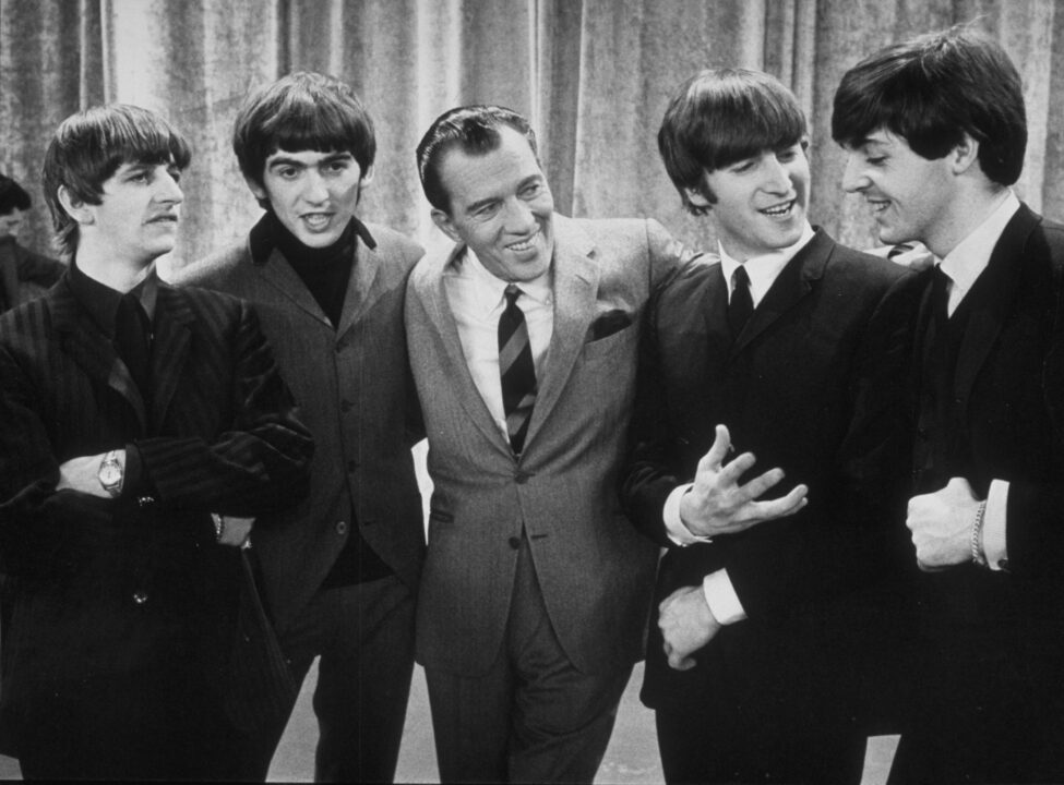 American television host Ed Sullivan (center) smiles as he stands, with the members of British rock group the Beatles, on the set of his television variety series, 'The Ed Sullivan Show' at CBS's Studio 50, New York, New York, February 9, 1964. Pictured are, from left, Ringo Starr, George Harrison, Sullivan, John Lennon, and Paul McCartney. The photo was taken during prior to the group's debut performance on the show later that day. 