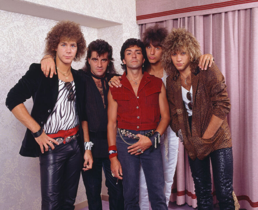 Gutchie Kojima/Shinko Music/Getty Images) US rock band Bon Jovi, group portrait in a hotel room during their first visit to Japan, Nagoya Kanko Hotel, Aichi, Japan, 4th August 1984. (L-R) David Bryan, Tico Torres, Alec John Such, Richie Sambora, Jon Bon Jovi