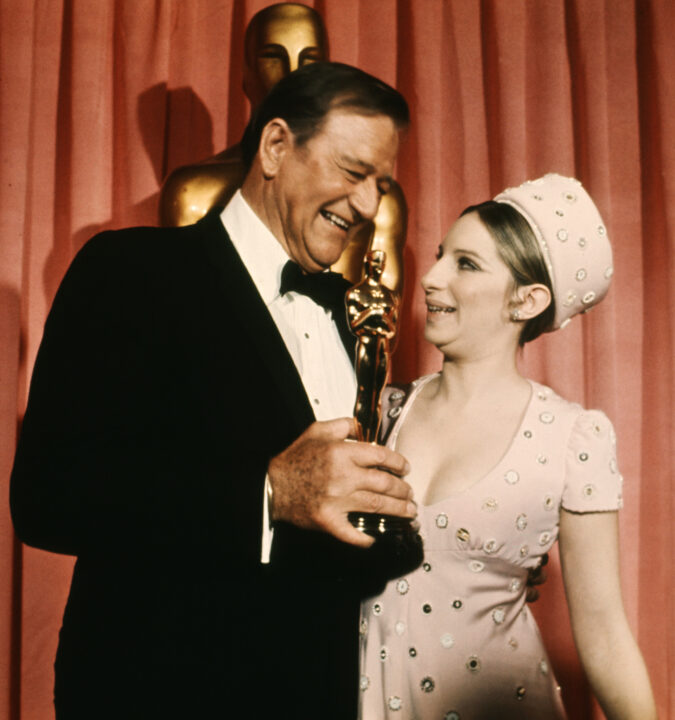 HOLLYWOOD, FL - JANUARY 1: Picture dated from 1969 of American actor John Wayne (1907 - 1979) holding an Oscar that he was awarded for his role in True Grit. On right, American actress and singer Barbra Streisand. 