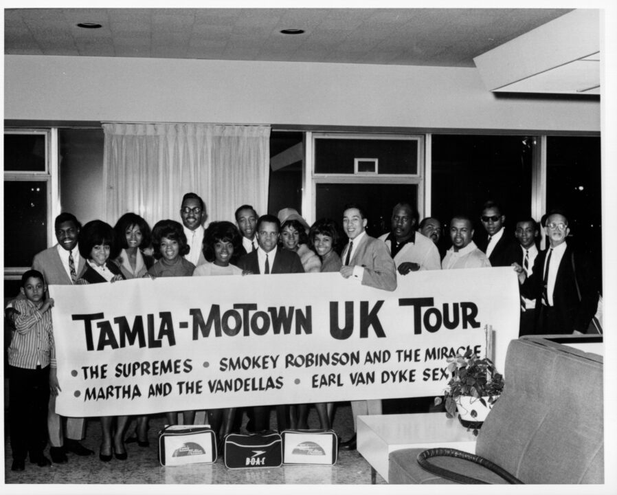 UNITED STATES - CIRCA 1960: Photo of performers and staff members of Motown Records as they pose in an airport with a sign that reads, in part, 'Tamla-Motown UK Tour,' March 1965. 