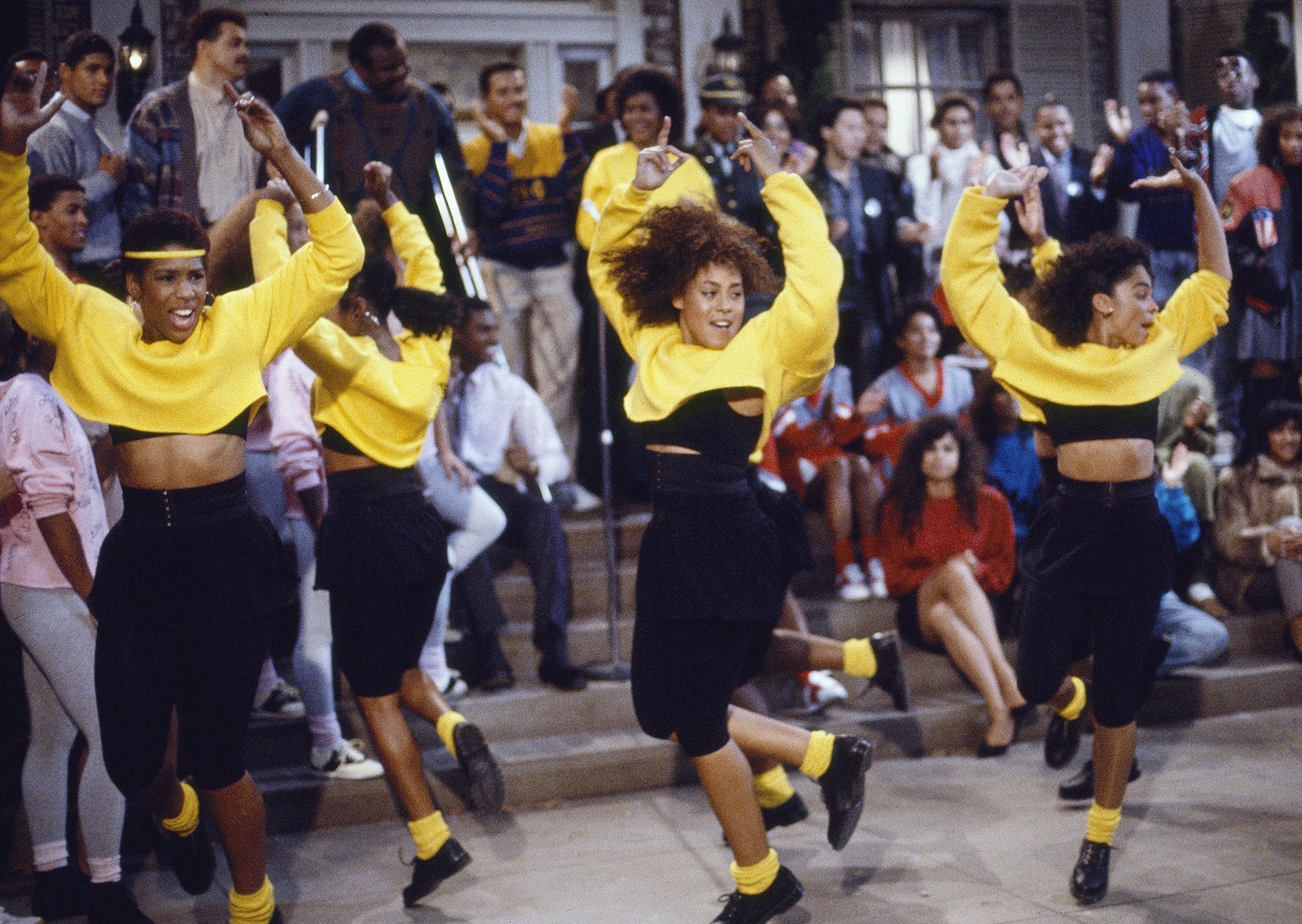 Picture from a 1988 episode of NBC's "A Different World." From left to right are Dawnn Lewis as Jaleesa Vinson Taylor, Cree Summer as Winifred "Freddie" Brooks and Jasmine Guy as Whitley Marion Gilbert Wayne. The three women are wearing yellow tops and black pants, and have their arms raised in the air as they dance at an event.
