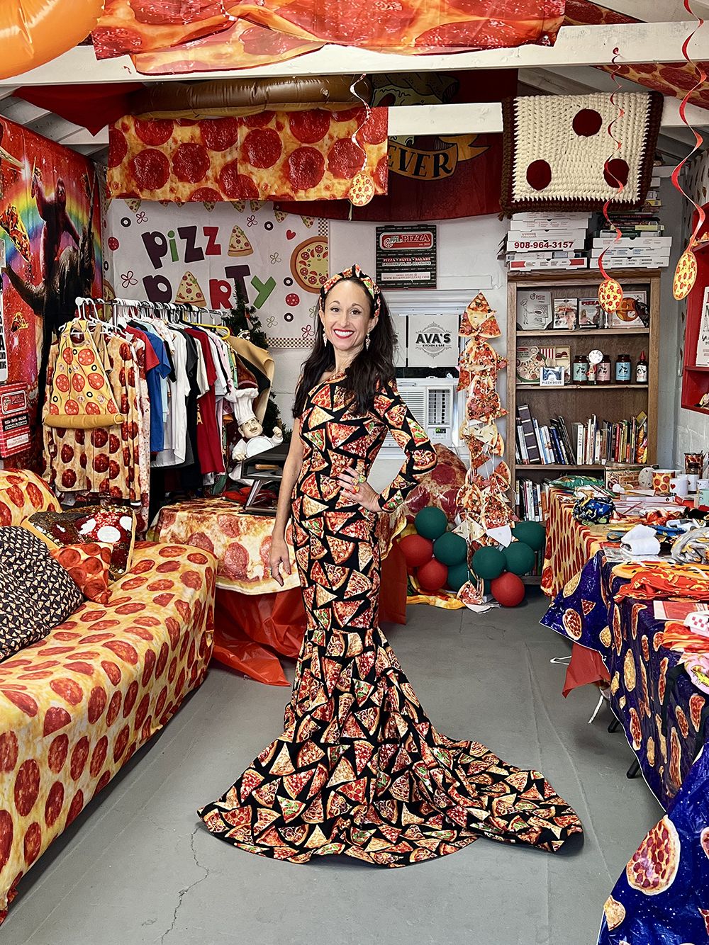image from a Season 5 episode of MeTV's "Collector's Call." Telina Cuppari, who collections pizza-related items, is modeling her "pizza dress" as she smiles and is surrounded by various other pizza-themed objects from her collection.