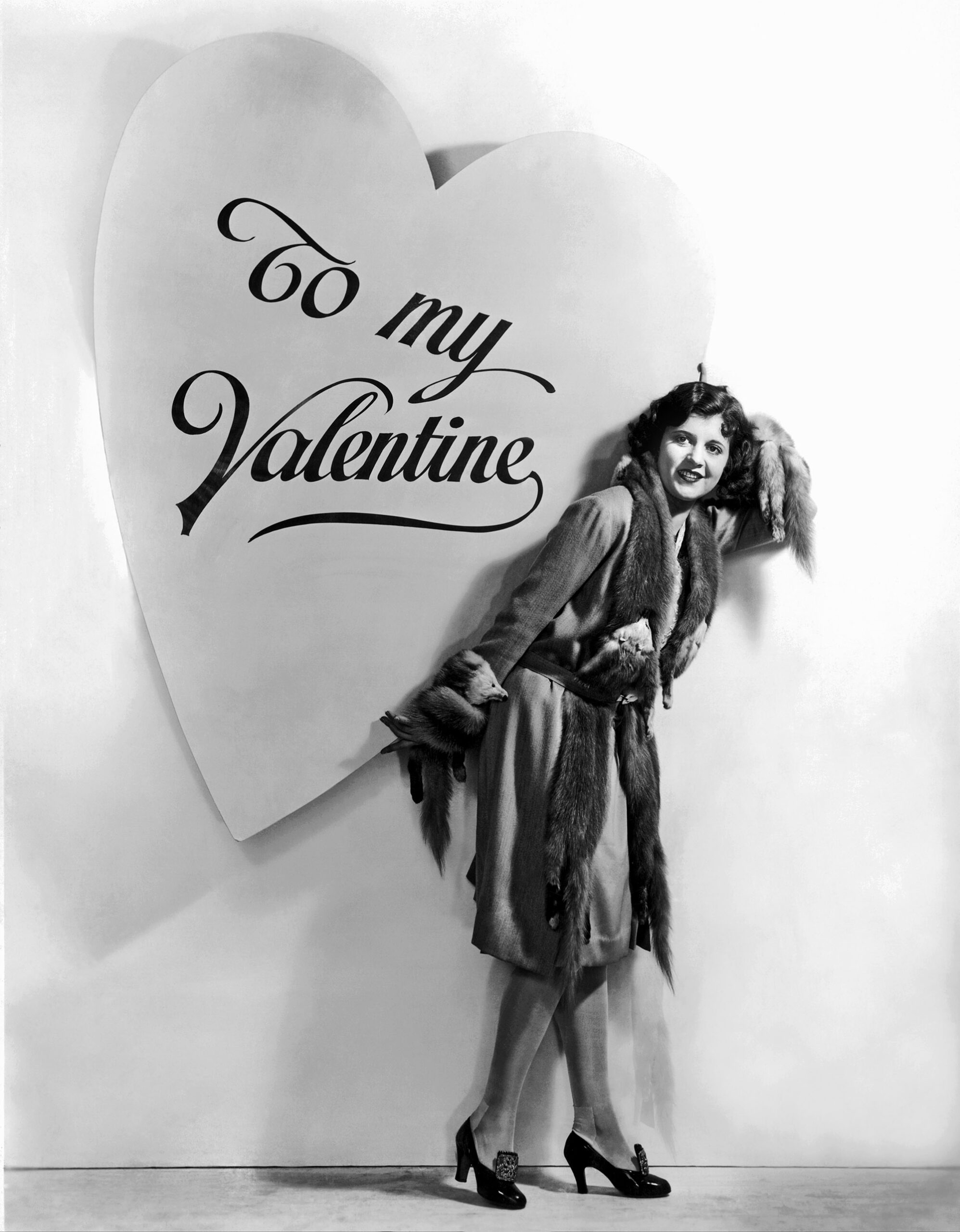 Actress Dorothy Gulliver poses against a backdrop of a large heart, in which reads: "To My Valentine" in this 1930s studio portrait.