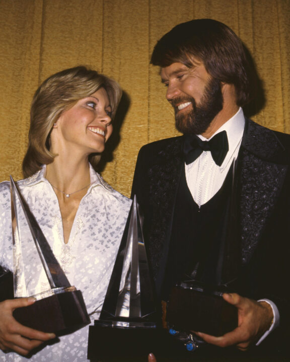 Singers Olivia Newton-John and Glen Campbell (1936 - 2017) with their awards at the American Music Awards, USA, 31st January 1976. Newton-John won two awards for Best Pop/Rock Album ('Have You Never Been Mellow') and Favorite Pop/Rock Female Artist, and Campbell won the Favorite Pop/Rock Song award for 'Rhinestone Cowboy'. 