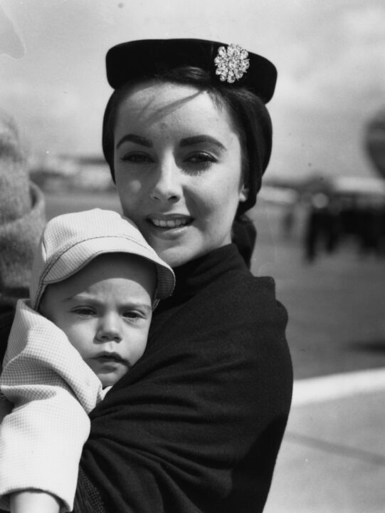 Actress Elizabeth Taylor holding her son Michael in her arms at an airport, August 25th 1953. 