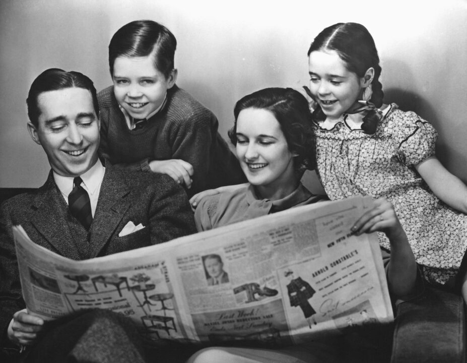 UNITED STATES - CIRCA 1950s: Family reading newspaper. 