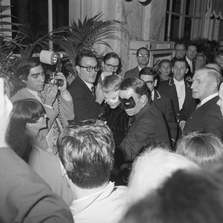 Reporters swarm Frank Sinatra and his wife, actress Mia Farrow, as they arrive at Truman Capote's Black and White Ball. The some considered the party, held at the Plaza in New York City, to be the biggest social event of the year.