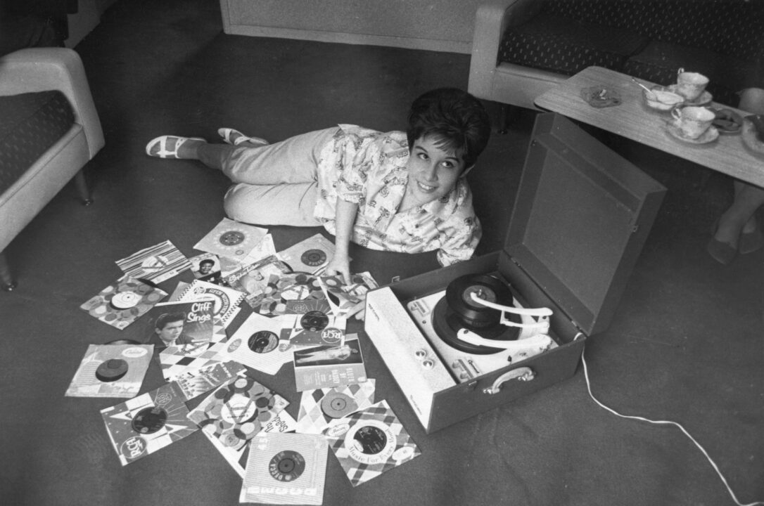Helen Shapiro, the pop singer who had greatest success in the early 60's, lying on the floor playing records on her Dansette gramophone player. 