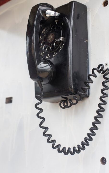 Vintage black rotary dial telephone hanging on the wall