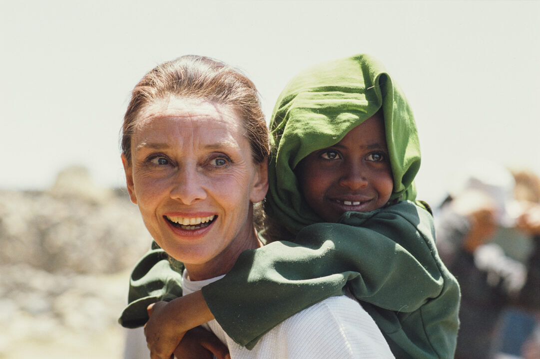 British actress and humanitarian Audrey Hepburn (1929 - 1993) carrying an Ethiopian girl on her back while on her first field mission for UNICEF in Ethiopia, 16th-17th March 1988. 