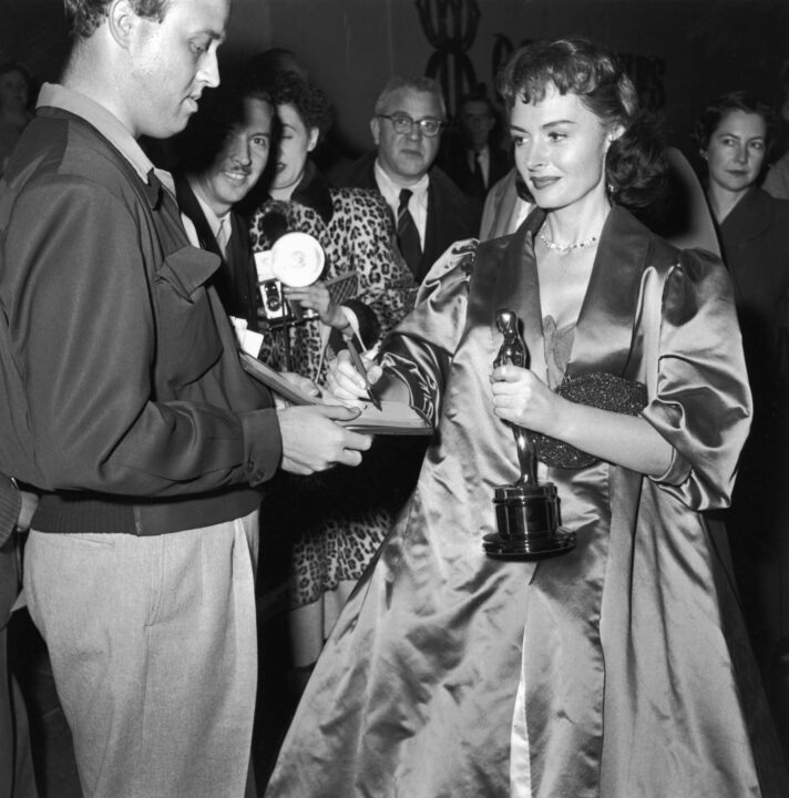 American actor Donna Reed (1921 - 1986) signs an autograph while holding her Oscar trophy at the Academy Awards, Los Angeles, California, March 25, 1954.