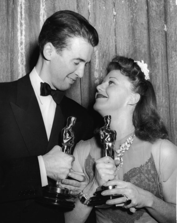 American actors James Stewart (1908 - 1997) and Ginger Rogers (1911 - 1995), arms locked and Oscars in hand, gaze into each other's eyes at the 1940 Academy Awards banquet, Los Angeles, California, February 27, 1941. Stewart won Best Actor in a Leading Role for his performance in 'The Philadelphia Story' while Rogers won Best Actress in a Leading Role for her performance in 'Kitty Foyle: The Natural History of a Woman.'