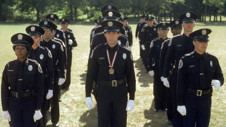POLICE ACADEMY, Bruce Mahler (third row left), Kim Cattrall (second row left), Marion Ramsey (front left), Steve Guttenberg (with medal), 1984,