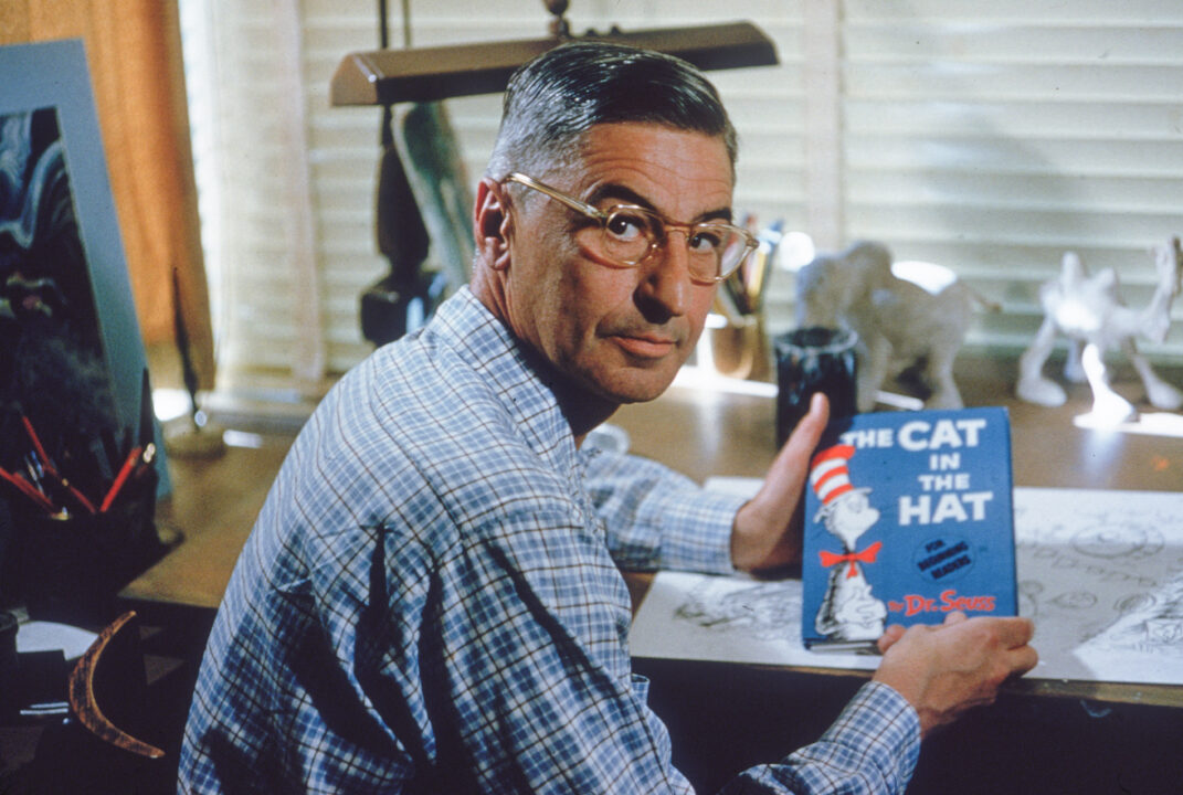 American author and illustrator Dr Seuss (Theodor Seuss Geisel, 1904 - 1991) sits at his drafting table in his home office with a copy of his book, 'The Cat in the Hat', La Jolla, California, April 25, 1957. 
