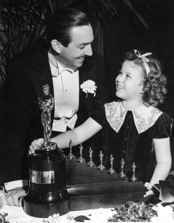 Shirley TempleShirley Temple Gives "Acadamy Awards" Trophies to Walt Disney for "7 Dwarfs" Los Angeles, Calif.: Above: Walt Disney and Shirley Temple are pictures standing by the large statue and seven small statuettes presented Disney by Miss temple for his outstanding cartoon, "Snow White and the Seven Dwarfs." Miss Temple made her presentation to Disney during the eleventh annual dinner of the Academy of Motion Picture Arts and sciences, held at the Biltmore Hotel, during which Spencer Tracy and Bette Davis were honored for their outstanding motion picture performances of the year. 2/24/1939