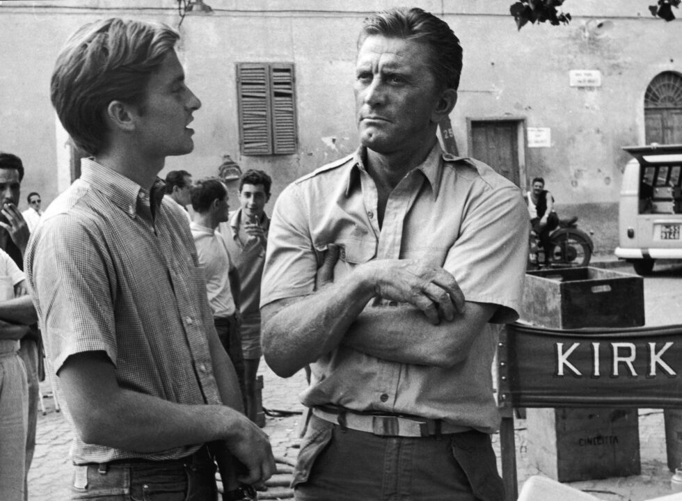 American actor Kirk Douglas (right) and his son American actor Michael Douglas on the set of the film, 'Cast a Giant Shadow,' directed by Melville Shavelson, Rome, Italy, 1965. Kirk had the starring role and Michael had a bit part.