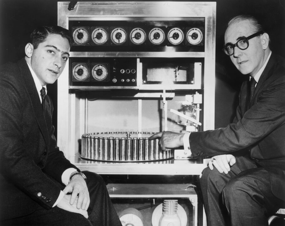 circa 1959: American film producer Mike Todd Jr (left) sits with Swiss inventor Hans Laube, who points to his 'Smell-O-Vision' machine, which produced smells in synchronization with action in a film. The device was used for director Jack Cardiff's 1960 film, 'The Scent of Mystery,' produced by Todd. 