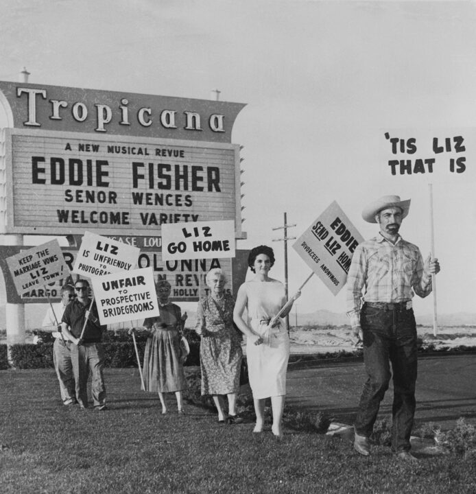 (Original Caption) Protest Fisherå-Taylor romance...A sign-carrying group demonstrates in front of the Tropicana Hotel here April 2nd, where Eddie Fisher opened an engagement April 1st. The demonstrators are protesting the singer's romance with actress Elizabeth Taylor. The pickets dispersed after a 30-minute demonstration before Fisher's show. Actress Debbie Reynolds announced April 2nd that she would grant ex-husband Eddie Fisher permission for a quickie Nevada divorce. This would leave him free to marry Miss Taylor after establishing residency in Nevada. Fisher and Miss Taylor announced their plans to wed at a a press conference following the singer's April 1st opening at the Tropicana.