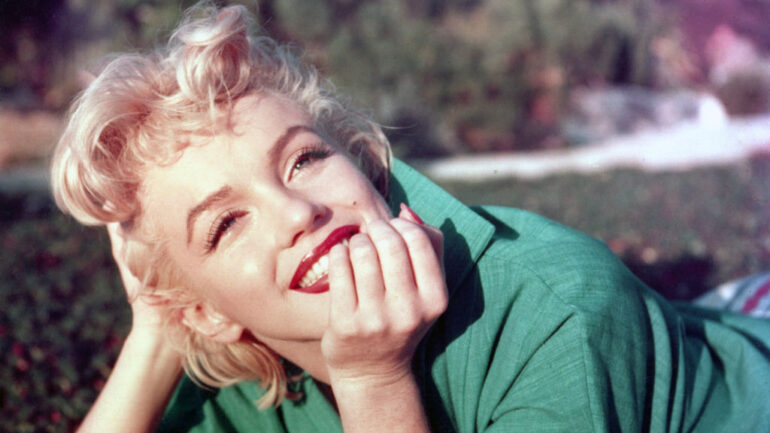 Actress Marilyn Monroe poses for a portrait laying on the grass in 1954 in Palm Springs, California