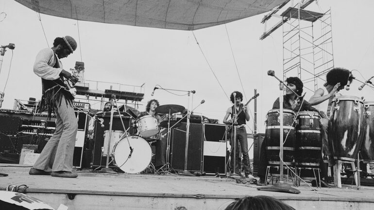 American bassist David Brown (left) performs with the other members of Santana, including drummer Michael Shrieve (behind drums), Mexican-born bandleader Carlos Santana (with guitar, center), and percussionists Michael Carabello (2d right) and Jose Areas (far right), at 'Woodstock,' a large rock and roll music concert, Bethel, New York, August 16, 1969. (Photo by Tucker Ransom/Getty Images)