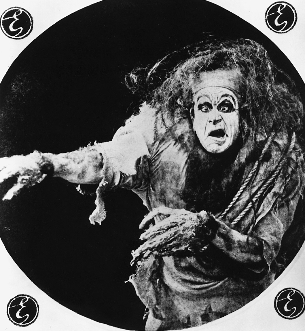 image from the 1910 silent film "Frankenstein." It depicts actor Charles Ogle as the Frankenstein monster, wearing ragged clothing and with a distorted look on his face as he holds out his clawed hands.