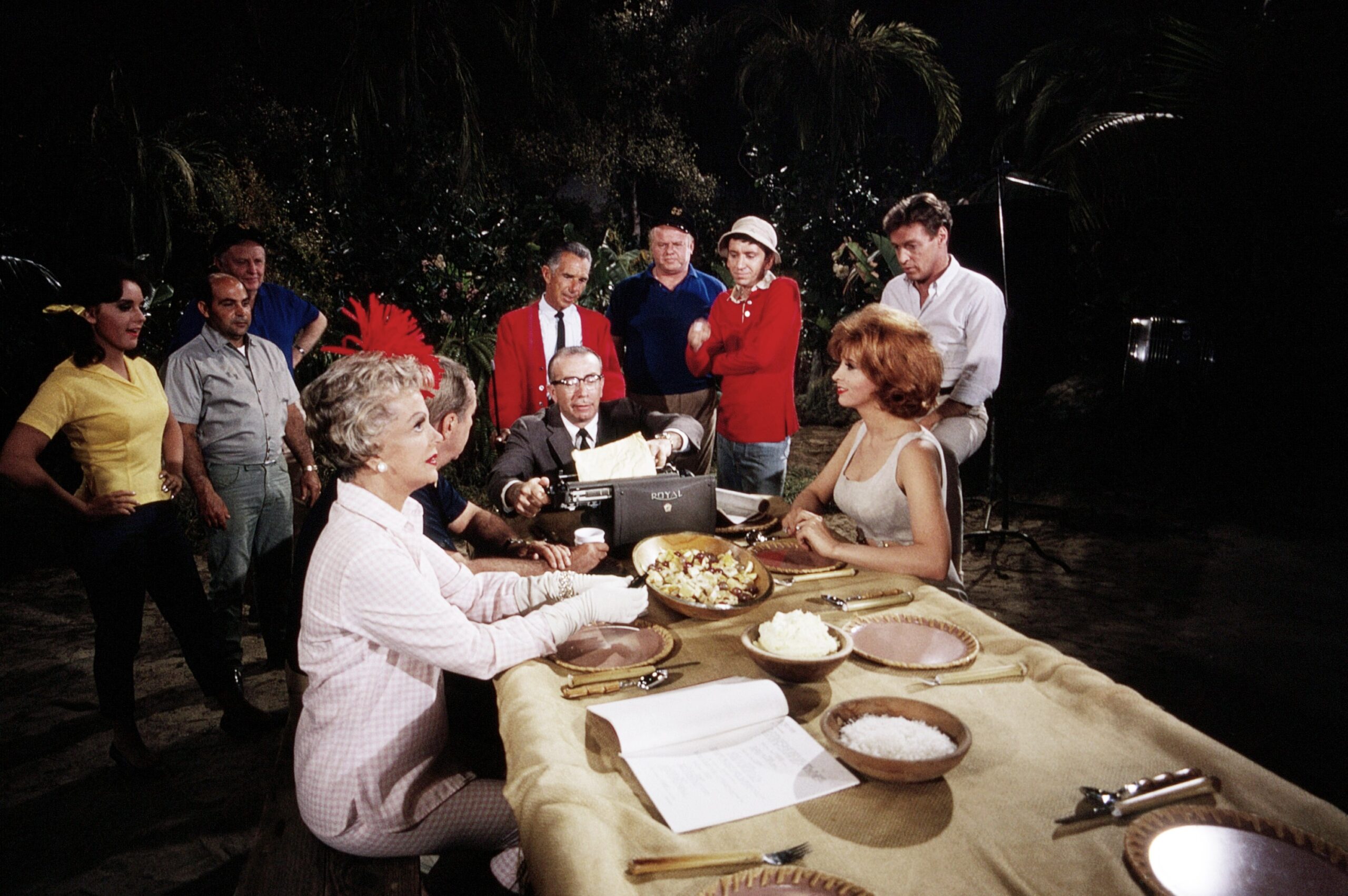 GILLIGAN'S ISLAND, from left, Dawn Wells, Natalie Schafer, Jim Backus, writer and producer Sherwood Schwartz, (at typewriter), Alan Hale, Jr., Bob Denver (in bucket hat), Tina Louise, Russell Johnson, on-set, 1964-67 (1965 photo).