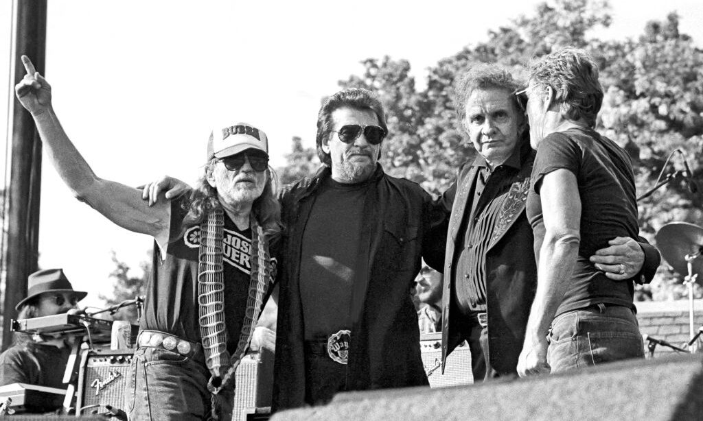 American country music group the Highwaymen, from left, Willie Nelson, Waylon Jennings, Johnny Cash (1932 - 2003), and Kris Kristofferson, embrace onstage at Central Park SummerStage, New York, New York, May 23, 1993