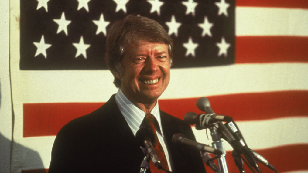 U.S. president Jimmy Carter smiling at a podium in front of an American flag, 1970s