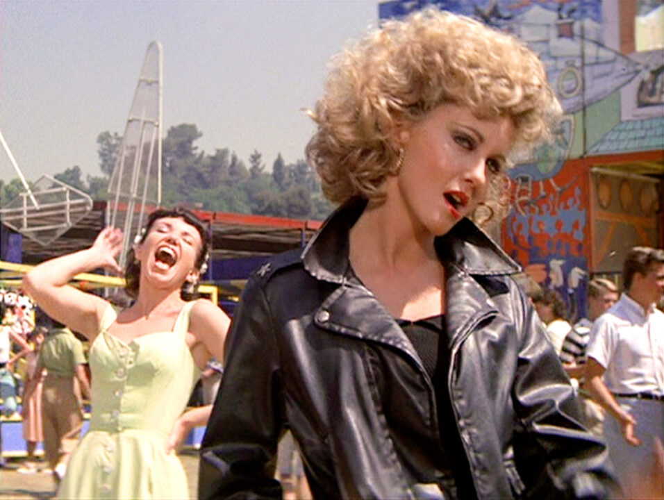 LOS ANGELES - JUNE 16: The movie "Grease", directed by Randal Kleiser. Seen here from left, Jamie Donnelly as Jan and Olivia Newton-John (in foreground, wearing tight black) as Sandy. Initial theatrical release of the film, June 16, 1978. Screen capture. Paramount Pictures.