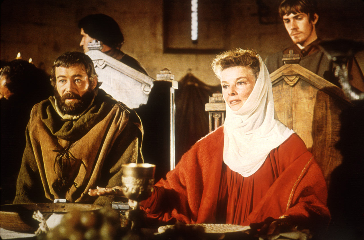 image from the 1968 historical drama "The Lion in Winter." Seated at a banquet table, dressed in 12th-century attire, are, on the left, Peter O'Toole as Henry II, and, to his left, on right of photo, Katharine Hepburn as Eleanor of Aquitaine