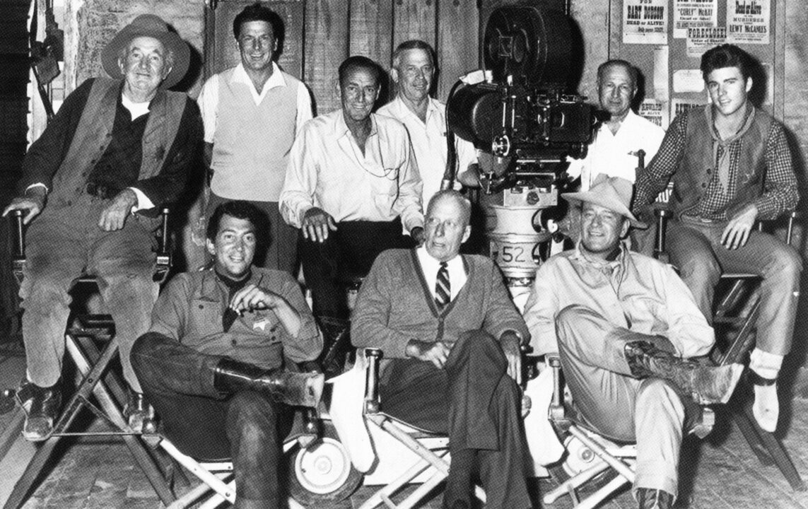 RIO BRAVO, seated front from left: Dean Martin, director Howard Hawks, John Wayne, seated center from left: Walter Brennan, cinematographer Russell Harlan, Ricky Nelson on set, 1959