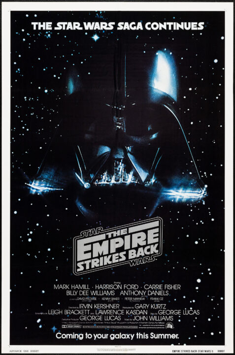 advance poster for the 1980 Star Wars movie The Empire Strikes Back. It is a vertical poster, and the backdrop is the black of space with stars. Silhouetted against this, in the center, is a large outline of Darth Vader's black helmet. On either side of this, and smaller, Imperial spacecraft go whooshing by. Above Vader's helmet, in white text in the Star Wars title font, reads: "The Star Wars Saga Continues". Just below the helmet is the film's stylized title treatment, below which is a list of the major credits. At the very bottom of the poster, in white text (using standard font), reads: "Coming to your galaxy this Summer."
