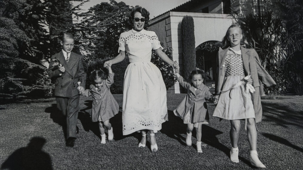 Joan Crawford and four children, Christopher, Cathy, Cynthia, and Christina romp on lawn following party given by Ann Rutherford for daughter Gloria's 5th birthday.