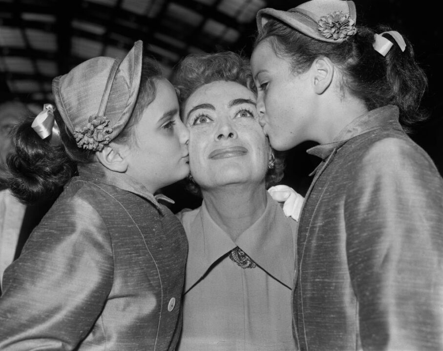 Actress Joan Crawford being kissed by two of her daughters, twins Cathy and Cynthia, London Paddington station, August 3rd 1956