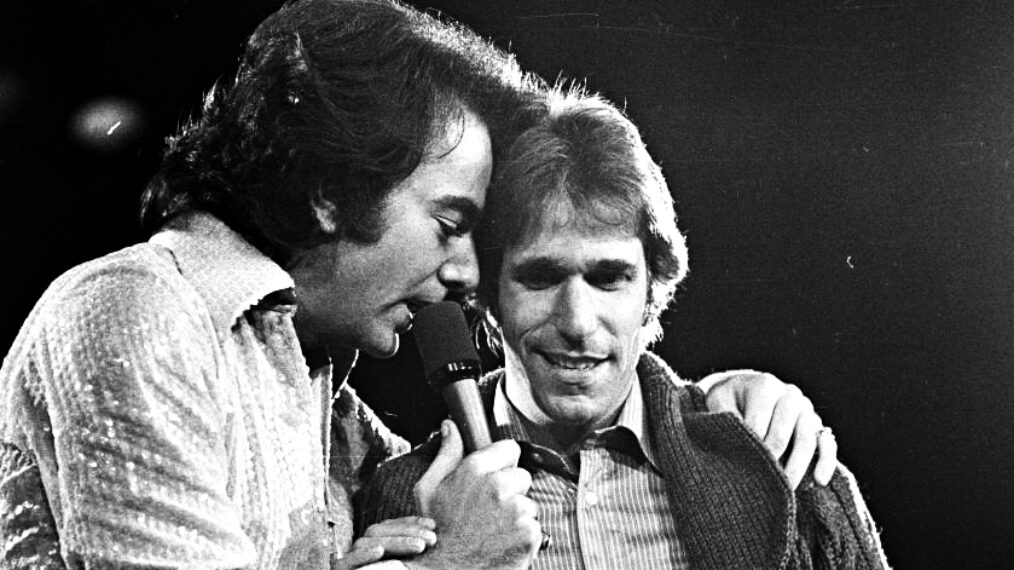 Singer Neil Diamond wearing a sequin shirt gets joined onstage by