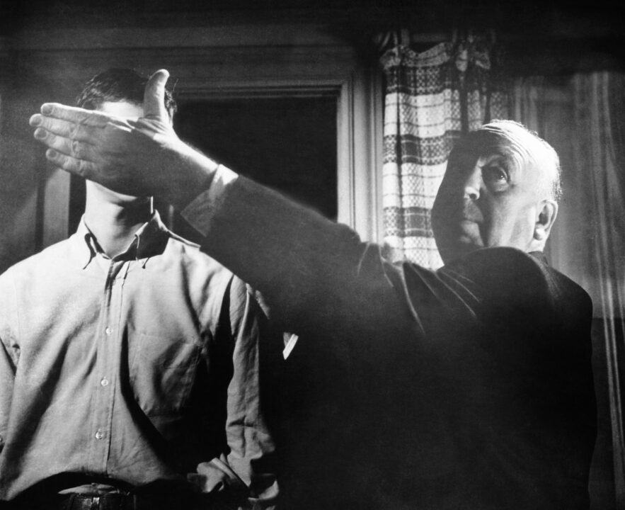 PSYCHO, director Alfred Hitcock blocks a scene for Anthony Perkins (back), on set, 1960