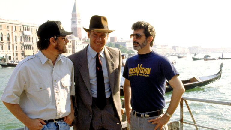 Director Steven Spielberg, Harrison Ford, producer George Lucas on the set of INDIANA JONES AND THE LAST CRUSADE, 1989