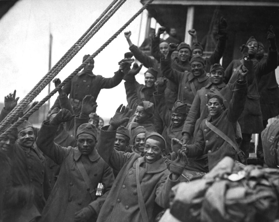 African Americans, members of the 369th Colored Infantry, wave from a troop ship as they arrive back in New York City. The regiment was nicknamed the Harlem Hellfighters and the Black Rattlers. Ca. 1919.