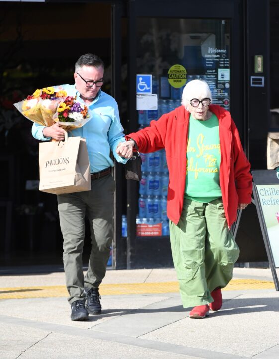 EXCLUSIVE. Coleman-RaynerMalibu, CA, USA. November 4, 2025 Shirley MacLaine, 91, nearly takes a tumble as she mis-steps whilst crossing a road in her Malibu neighborhood. The movie legend, who won a Best Actress Oscar in 1983 for her role in the family drama Terms of Endearment, was on her way to a fancy lunch at Lucky’s Steakhouse, an upscale eatery favored by celebrities including the Kardashians, on November 4, 2025. She wore a colorful outfit including green pants and matching colored sweater, a red overcoat and comfy slip-on shoes. Fortunately for Shirley she was holding onto the arm of a male friend when she slipped over, so she avoided a nasty fall. After dining for over an hour she brought two bags of food to go and popped into a local grocery store to grab several bouquets of flowers. CREDIT MUST READ: Jeff Rayner / Coleman-Rayner Tel US (001) 310-474-4343 – office www.coleman-rayner.com