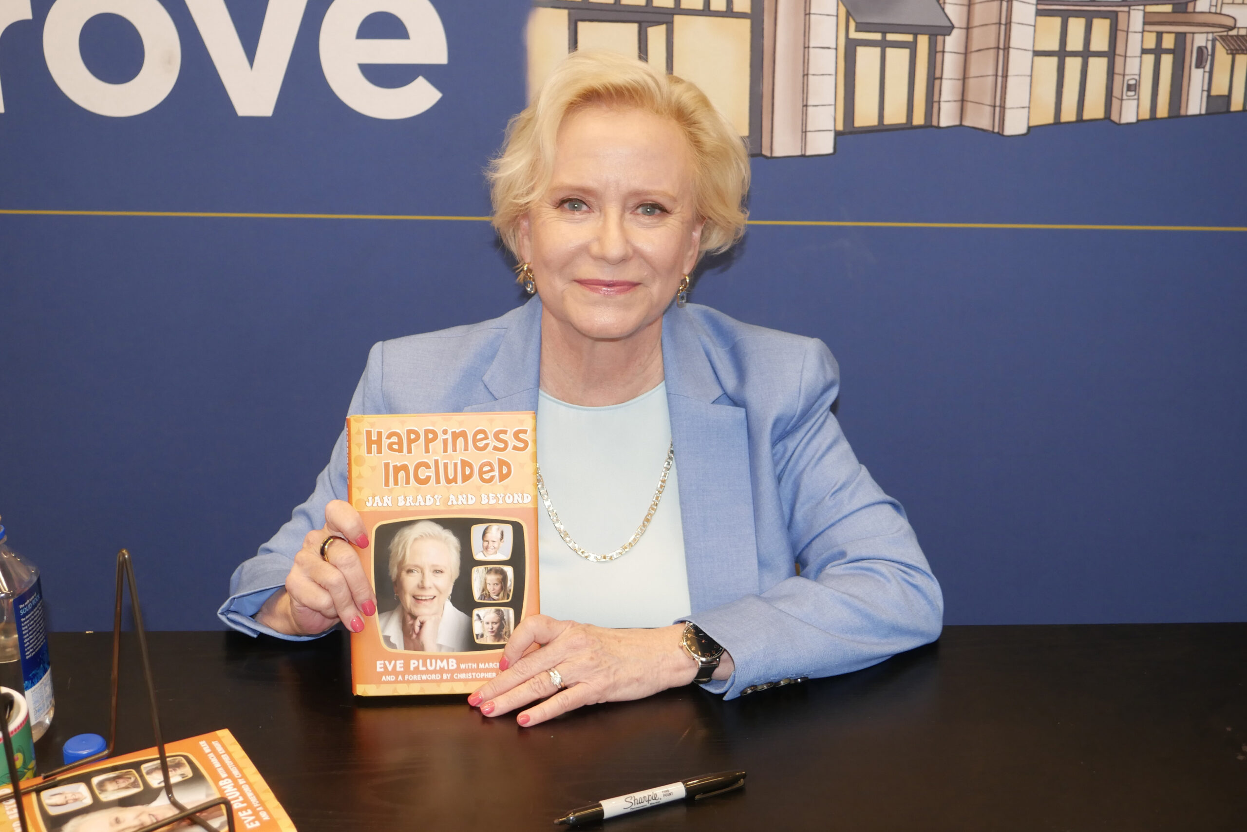 Eve Plumb from the Brady Bunch holding her new book