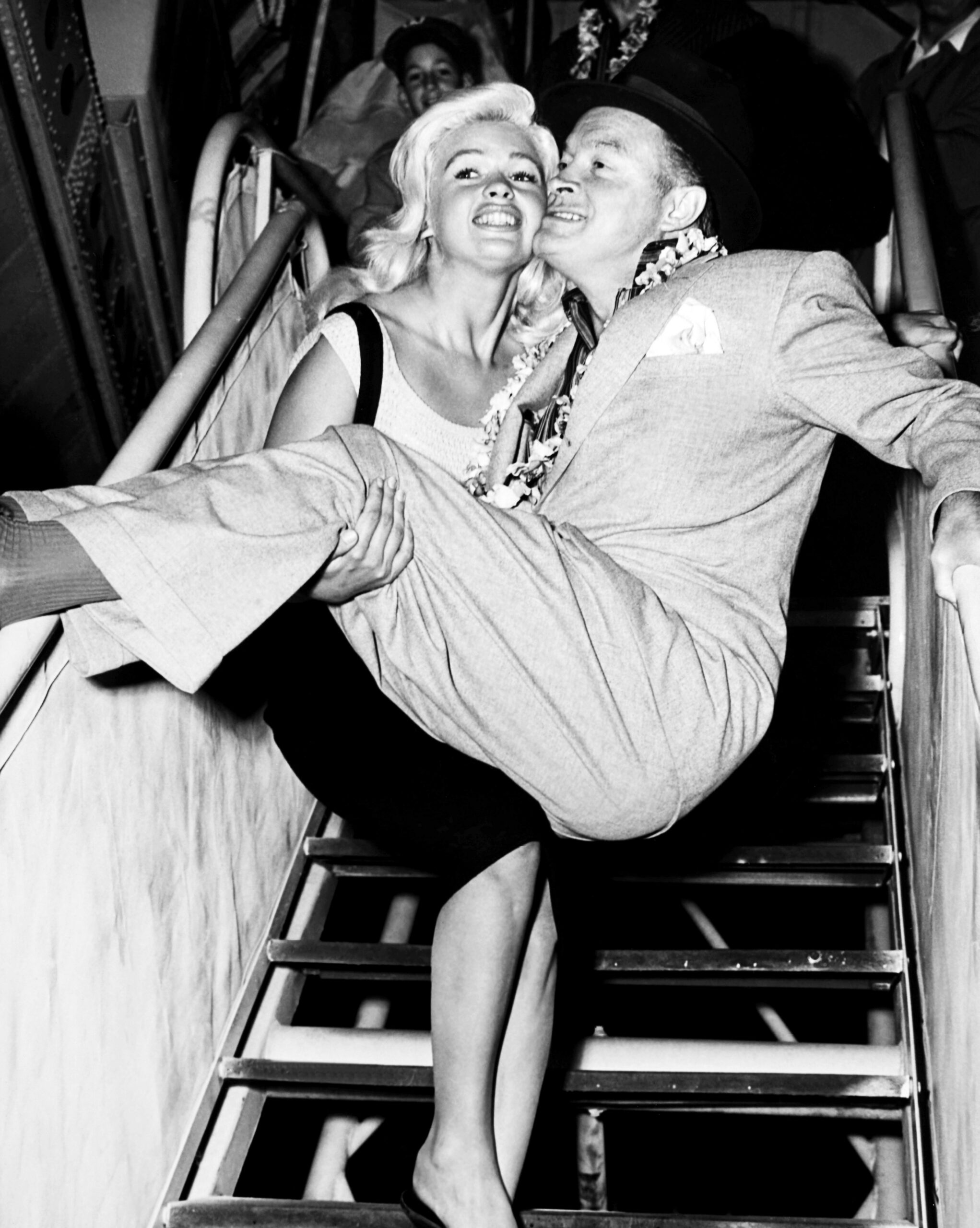 Jayne Mansfield, carriyng Bob Hope off a plane in Burbank, returning from a USO tour, December 1957