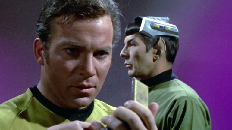 William Shatner as Captain James T. Kirk speaks into his communicator with Leonard Nimoy as Mr. Spock in the background in 'Star Trek' Season 3 Episode 1, 'Spock's Brain'