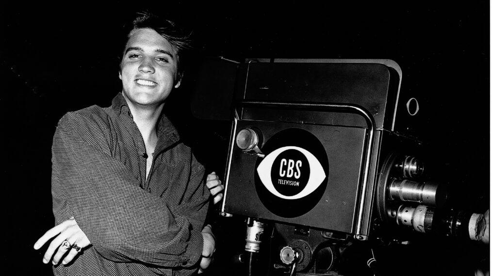 American singer and actor Elvis Aaron Presley (1935 - 1977) stands with his arms crossed by a television camera on the night of his first appearance on 'The Ed Sullivan Show,' CBS Television City studios, Los Angeles, California, September 9, 1956.